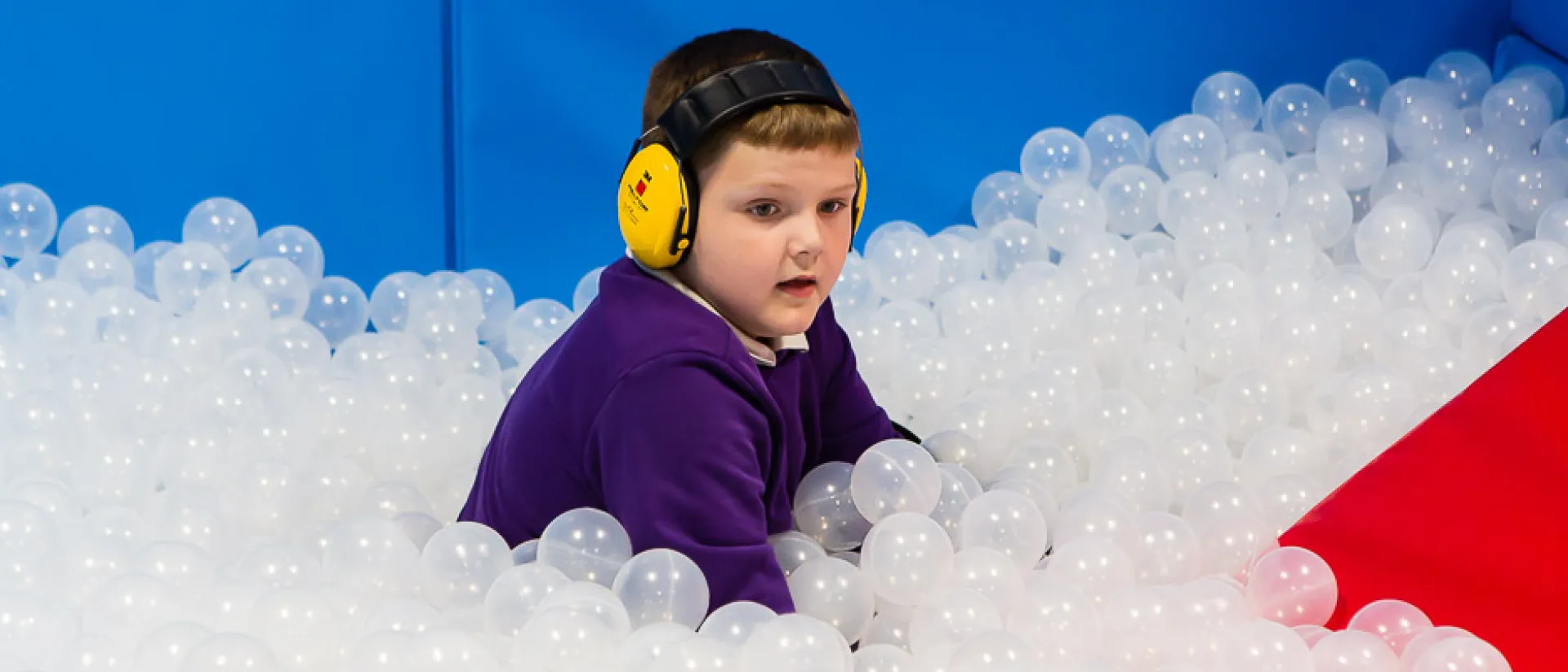 A child learning sensory skills in a ball pool.