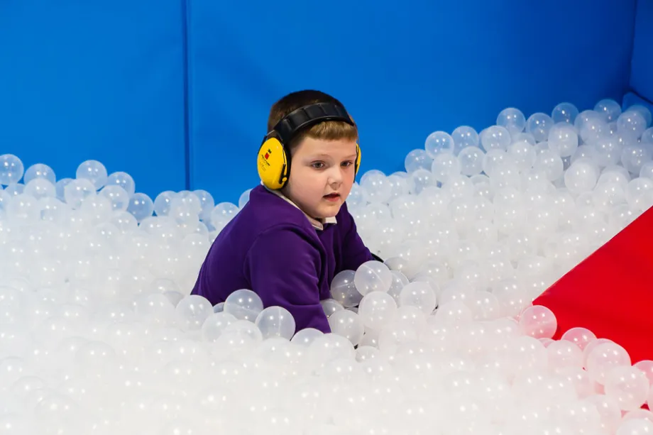 A child learning sensory skills in a ball pool.