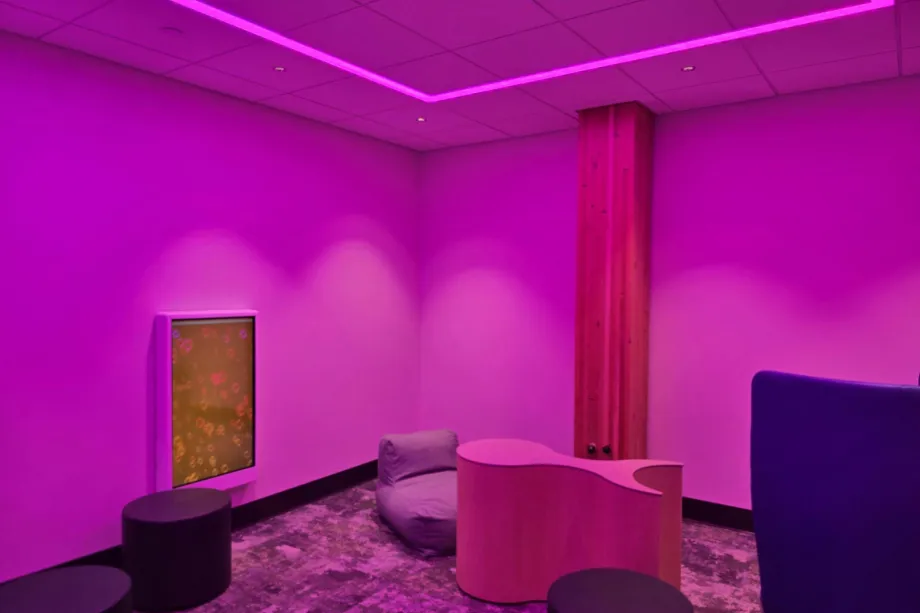 Sensory room in Hector Fargo airport. Showing interactive panels and soft furnishings lit by a pink light